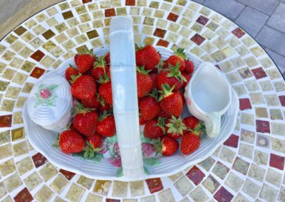strawberries and cream on a pretty white china set on terrazzo tile table