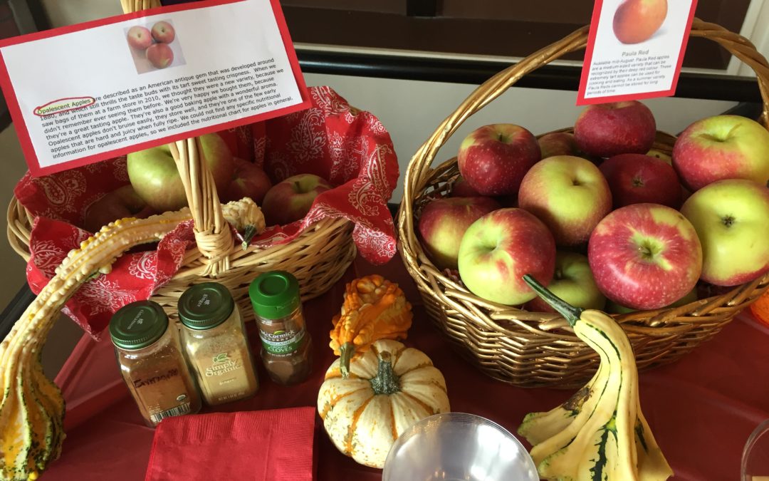 Table with two baskets of apples and squash and spice at Mondays At Racine