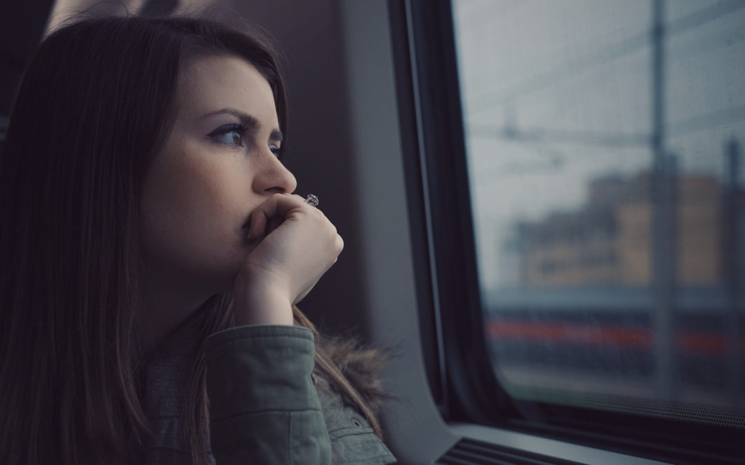 woman looking pensively out of window of train