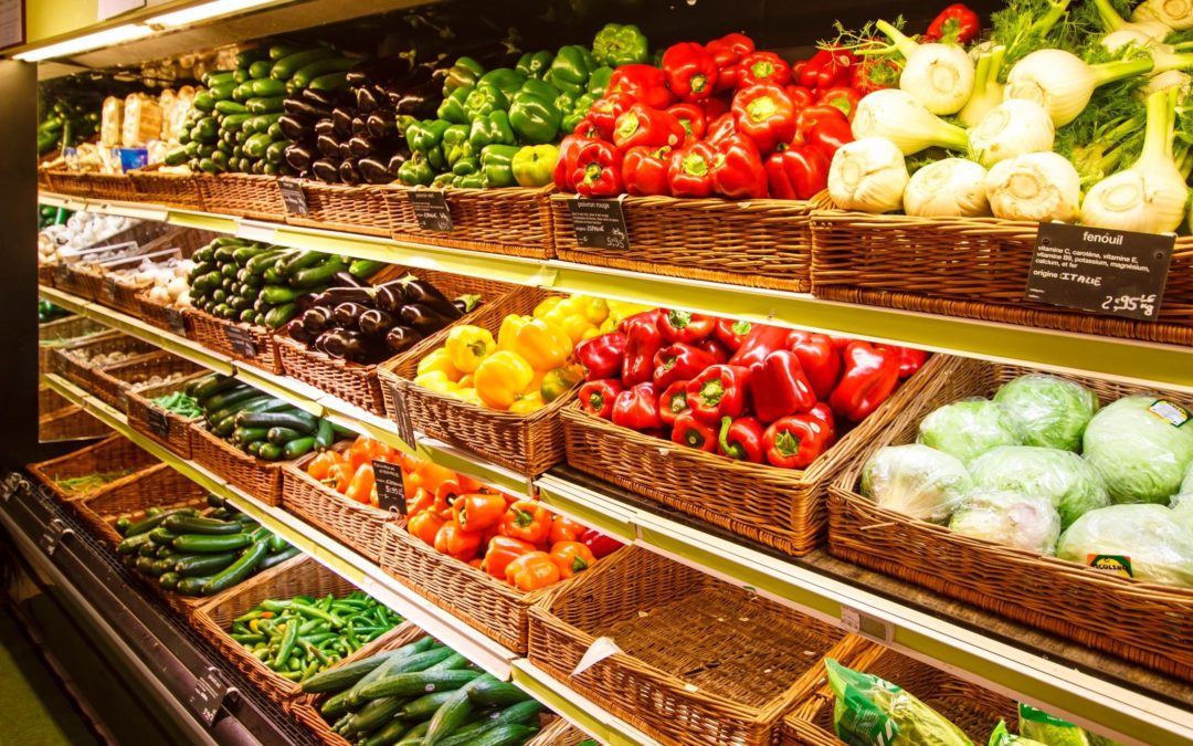Grocery produce shelves filled with vegetables like peppers , eggplant, cabbage, kohlrabi, zucchini