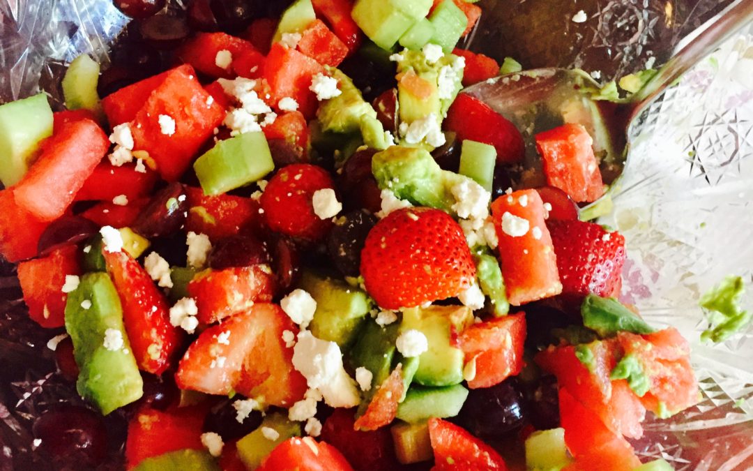 Summer Salad with watermelon and avocado is a pretty crystal bowl on red tablecloth